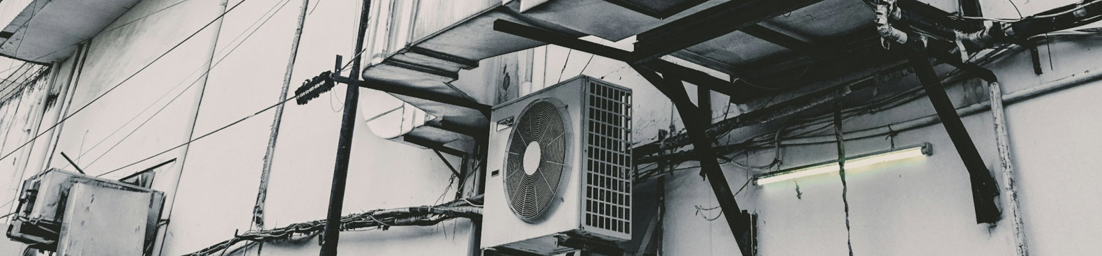 a black and white photo of an air conditioner on the side of a building
